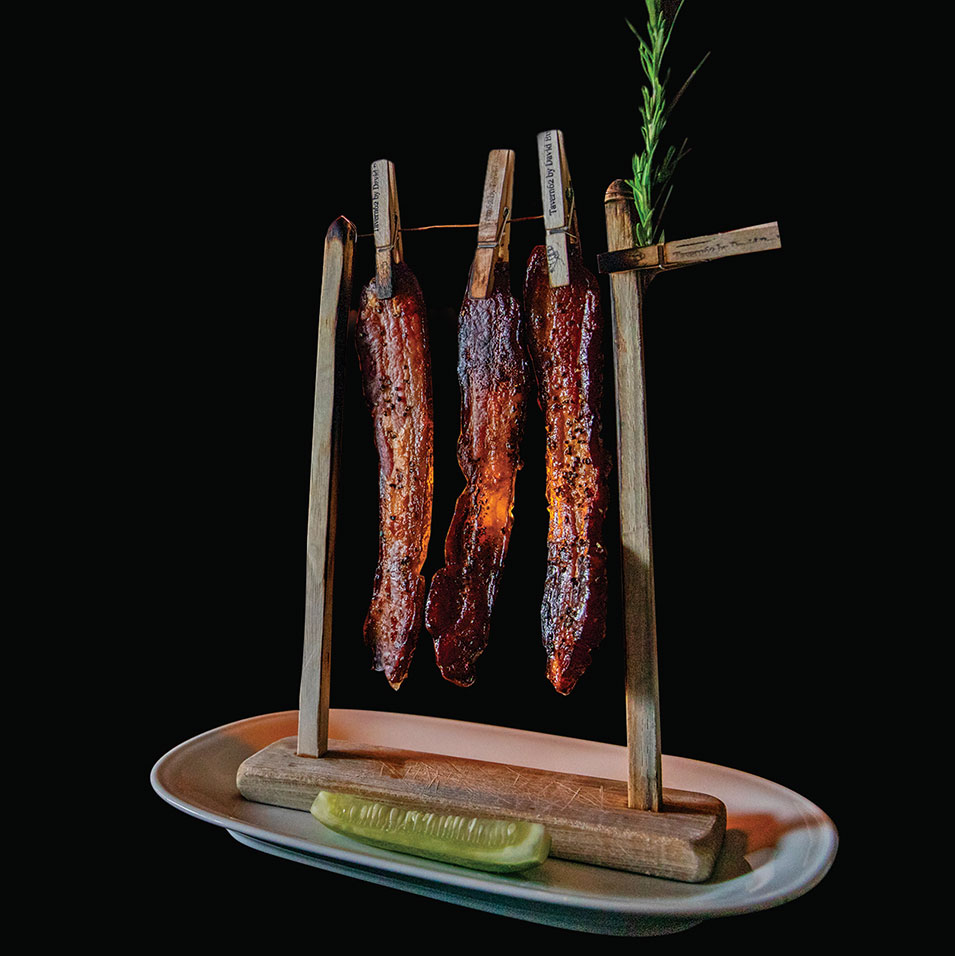 David Burke Roadshow's bacon-on-a-clothesline with a sprig of rosemary and a pickle