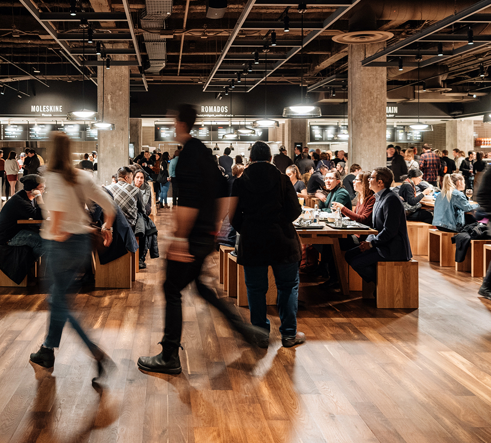 Scene of people eating at a communal table in Time Out Market Montreal