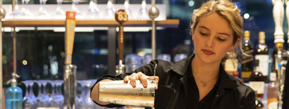 Female bartender pouring a mixed drink